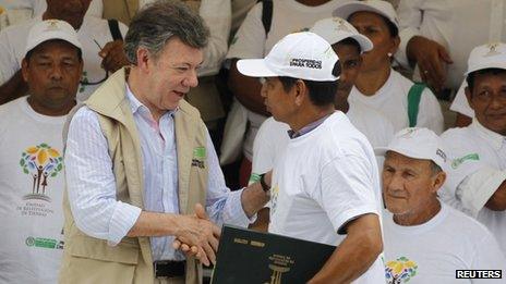 Juan Manuel Santos hands a land title to a displaced person on 10 April 2013
