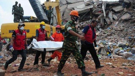 Members of the Bangladeshi army carry the body of a garment worker as heavy equipment is brought in to remove debris from the site