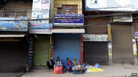 File photo: Street vendors sit on the sidewalk in front of closed shops in Nepal's capital, Kathmandu, 6 March 2013