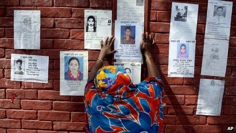 A woman grieves as she sticks a poster of a portrait of her family member on the wall of a school turned make-shift morgue on Tuesday 30, April, 2013