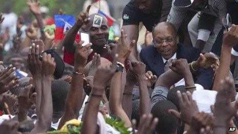 Former Haitian President Jean-Bertrand Aristide, right, greets supporters outside the courthouse in Port-au-Prince, Haiti, on Wednesday