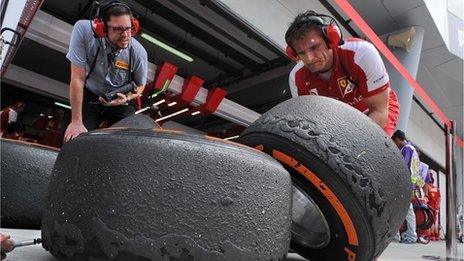 Ferrari driver Fernando Alonso and crew members look at the wear on tyres during the first practice session of the Formula One Malaysian Grand Prix