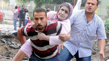 A resident evacuates an injured woman from the bomb scene in Reyhanli, Turkey, 11 May