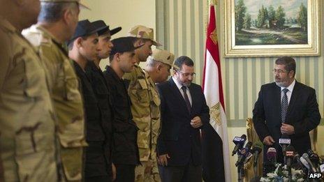 Egyptian President Mohammed Morsi (R) and Prime Minister Hisham Qandil (2R) welcome the policemen and soldiers (L) who were seized in Sinai by kidnappers at Almaza military Airbase in Cairo on Wednesday following their release