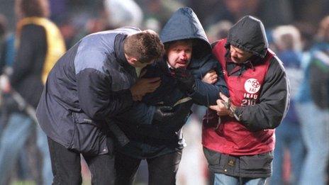 An injured fan is helped by stewards