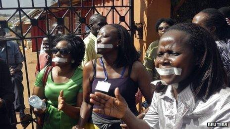 Employees of the Daily Monitor newspaper with their mouths taped shut, sing slogans during a protest against the closure of their premises by the Uganda government, outside their offices in the capital, Kampala, on 20 May 2013