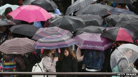 Passengers shelter under umbrellas as they wait on Westminster Pier on 28 May in London