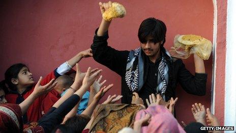 A Pakistani man distributes food to Muslim devotees at the shrine of the Sufi saint Mian Mir Sahib in Lahore in 2011