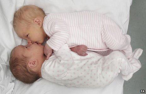 New-born Rodger twins lying face to face in a bed