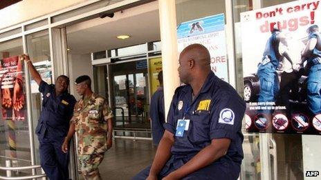 Security guards stand by anti-drug trafficking posters outside Kotoka International Airport, in Accra - 2007