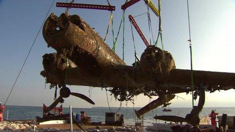 The rusted plane, missing part of a wing, held up by a crane