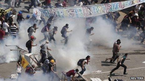 Protesters run as riot police fire teargas during a protest at Taksim Square in Istanbul