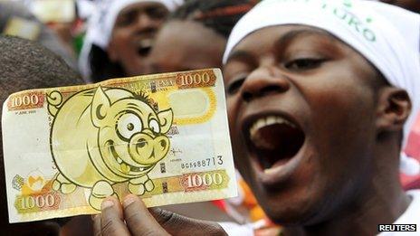 A protester displays a modified Kenyan bank note imprinted with an image of a pig in Nairobi during 11 June 2013