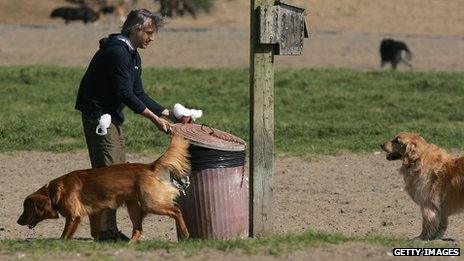 A man putting a dog poo bag in a bin