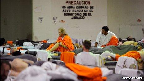 Inmates at Chino State Prison, which houses 5500 inmates, crowd around double and triple bunk beds in a gymnasium that was modified to house 213 prisoners