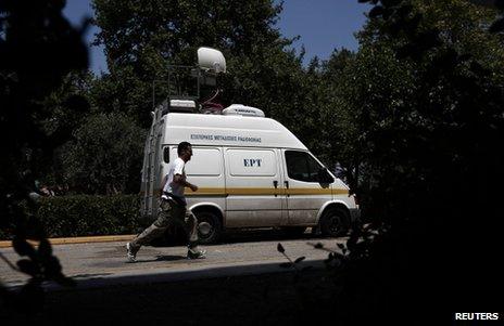A man runs past a van of Greek public broadcaster ERT outside its headquarters in Athens, 17 June