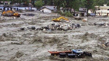 Bulldozer and other vehicles are drifted in a flooded river in Uttarkashi district, India, Monday, June 17, 2013