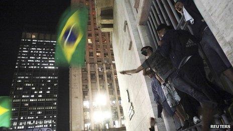 Demonstrators climb up the entrance gates of City Hall in Sao Paulo