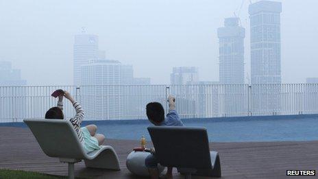 A couple take a picture of the smog-filled skyline in Singapore on 19 June 2013