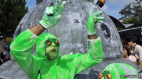 A man in a green costume in front of a UFO