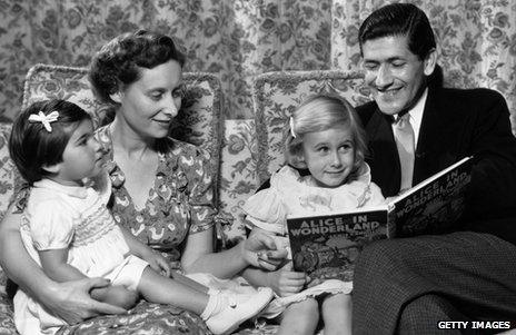 An old photo of parents reading Alice in Wonderland to their children