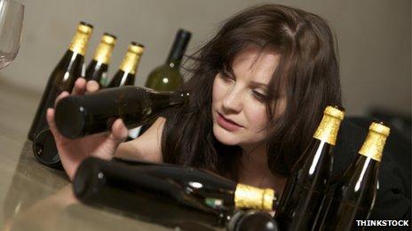 A drunk woman is looking into an empty bottle