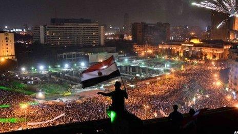 Egyptians wave national flag on rooftop as thousands demonstrate in Tahrir square