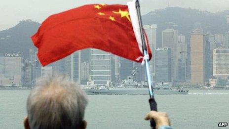 File photo: An elderly supporter waves a Chinese flag as a ship from a Chinese People Liberation Army Navy task group passes the Victoria harbour skyline in Hong Kong, 5 May 2004