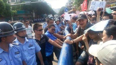 Police stand across demonstrators during a protest against plans for a uranium processing plant in Jiangmen, Guangdong province, 12 July 2013. The placard reads "Anti-nuclear"