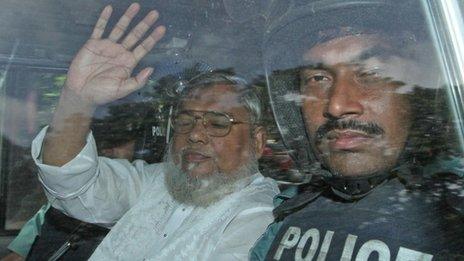 Mohammad Mujahid (L) waves from a police vehicle as he is transported to the central jail following his court verdict in Dhaka on 17 July
