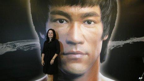 Shannon Lee, daughter of the late Kung Fu star Bruce Lee, poses in front of a promotional poster for Lee"s memorial exhibition at the Hong Kong Heritage Museum Thursday, July 18, 2013,
