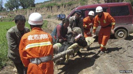 Firefighters carry an injured woman on a stretcher after a 6.6 magnitude earthquake hit Minxian county, Dingxi, Gansu province 22 July 2013