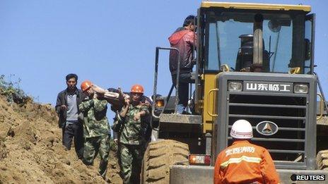 A victim is carried out on a stretcher next to an excavator after a 6.6 magnitude earthquake hit Minxian county, Dingxi, Gansu province 22 July 2013