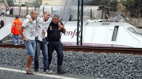 Rescue workers help a victim of the derailed train near Santiago de Compostela