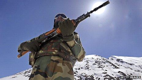 An Indian soldier standing guard on a mountainous road in the border area