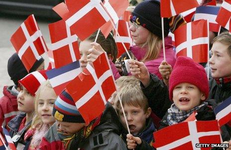 Danish children crowded together waving Danish flags