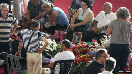People mourn next to the coffins of victims of a coach crash before the start of the funeral service at the Monteruscello Palasport near Pozzuoli July 30, 2013.