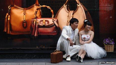 A young couple sit in front of a Gucci shop in Vietnam