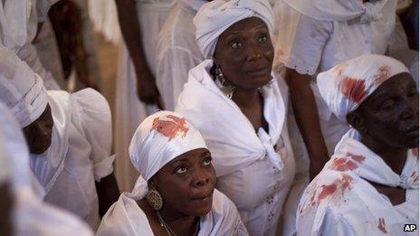 Women wearing clothes stained with blood from a sacrificed animal attend a Voodoo ceremony in Souvenance, Haiti, on 24 April, 2011.