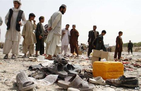 Afghan men walk amidst sandals, mostly from victims of a bomb blast, strewn at the roadside on the outskirts of Kandahar on August 5, 2013.