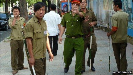Vietnamese police and local militia try to stop a photographer taking pictures