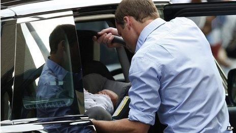 Prince William places his newborn son and his car seat into the car before leaving hospital on 23 July 2013