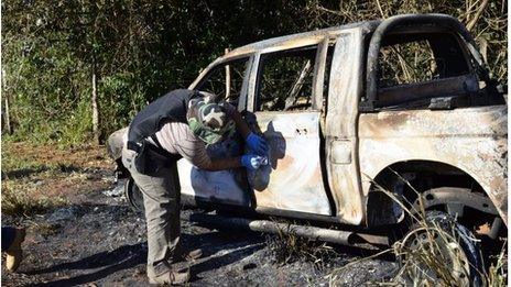 A burnt-out police vehicle is inspected by a officer in San Pedro, north of Paraguay, 18 August