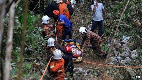 Malaysian emergency services personnel rescue a passenger (C) after a bus carrying tourists and local residents fell into a ravine near the Genting Highlands, about an hour's drive from Kuala Lumpur on August 21, 2013