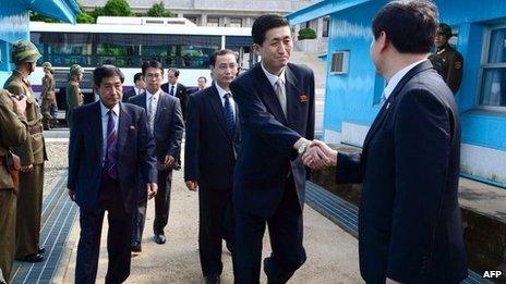 A South Korean official (R) greets a North Korean negotiation team for Red Cross talks as the team crosses the border line at the truce village of Panmunjom in the Demilitarized Zone dividing the two Koreas on 23 August 2013