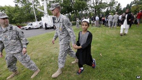A young Afghan villager boy named Khan holds the hand of US Army Master Sgt Timothy Gunther after a news conference at Joint Base Lewis-McChord, Washington state, on 23 August 2013