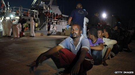 Migrants wait to board a bus after disembarking from a Maltese patrol vessel at Hay Wharf in Valletta, after being rescued on 10 July 2013