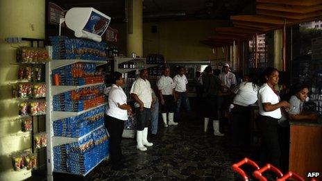 Employees of a supermarket closed due to a blackout, wait for power to be re-established, in Caracas on 3 September, 2013.