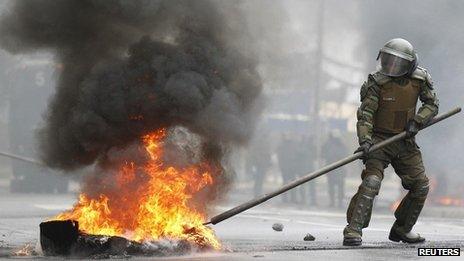 A riot police officer tries to extinguish burning tyres during a protest marking the military coup. September 4, 2013