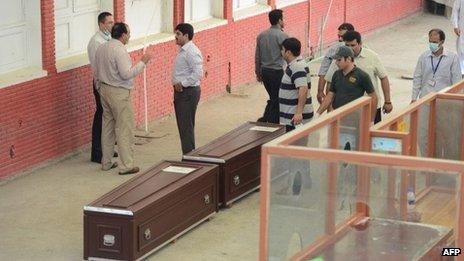 Pakistani and Slovakian officials stand next to the coffins of Slovakian climbers as they make arrangement to move them from the hospital in Islamabad on 27 June, 2013